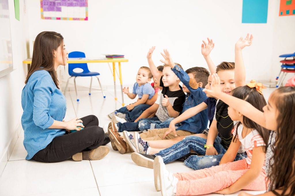 profile view group preschool students raising their hands trying participate school min